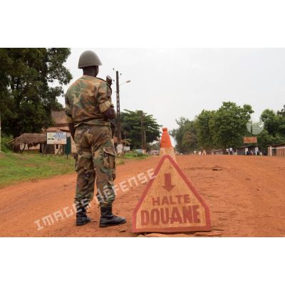 Soldat centrafricain en faction à côté d'un panneau des douanes à Bambari, installé dans le cadre de la réouverture des bureaux douaniers et l'installation dans la ville de l'ORCCPA (office de réglementation, de commercialisation et de conditionnement des produits agricoles).