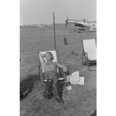 Portrait du lieutenant Franz von Werra du 1er groupe du Jagdgeschwader 53 " Pik As " (I./JG 53), assis dans une chaise longue, torse nu, fumant une cigarette.