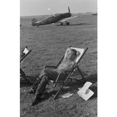 Portrait du lieutenant Franz von Werra du 1er groupe du Jagdgeschwader 53 " Pik As " (I./JG 53), assis dans une chaise longue, torse nu, fumant une cigarette.