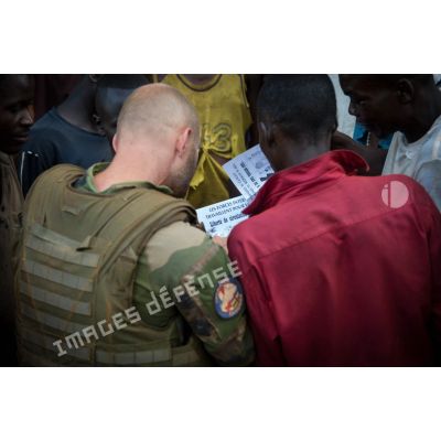 Un sous-officier d'une demi-section du GTIA (groupement tactique interarmes) Turco distribue des tracts à des habitants des alentours lors d'une reconnaissance d'axe entre Bindi et Bambari.
