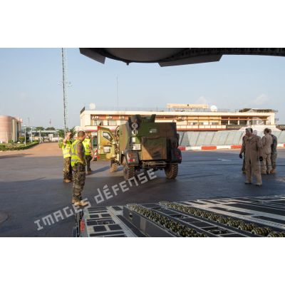 Aidés par le personnel navigant de l'US Air Force, les éléments du 1er RTP affecté au DéTIA (détachement de transit interarmées) procèdent au chargement d'un véhicule PVP (petit véhicule protégé) dans la soute d'un avion Douglas C-17 stationnant sur le tarmac de l'aéroport M'Poko de Bangui, dans le cadre du désengagement progressif de la force Sangaris.