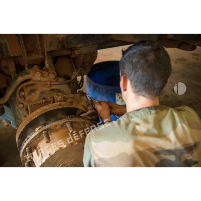 Un mécanicien effectue une réparation sur la roue d'un véhicule, à l'atelier de réparation mécanique du train de combat du camp de M'Poko de Bangui.