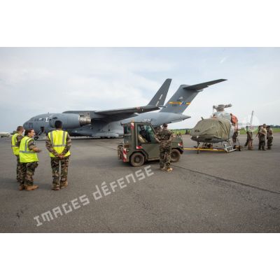Préparation au chargement de deux hélicoptères Fennec AS-555 AN du DETFENNEC (détachement Fennec) dans la soute d'un avion cargo Douglas C-17 de la Air Mobility Wing de l'US AIr Force, par deux tracteurs industriels et d'aéroport Tracma, dans le cadre de leur désengagement depuis le camp M'Poko de Bangui.