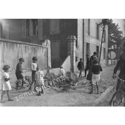 Des enfants jouent dans une rue de Nancy près d'un porche détruit.