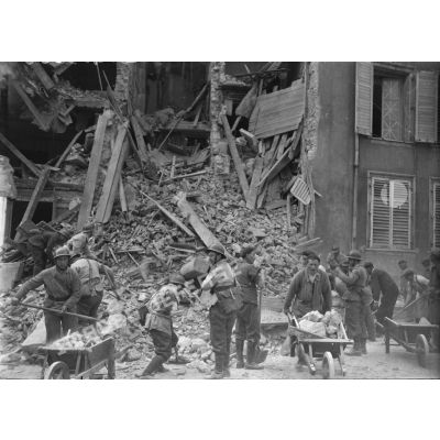 Des civils et des hommes de la défense passive évacuent les gravats d'une maison détruite par le bombardement allemand sur la ville de Nancy.