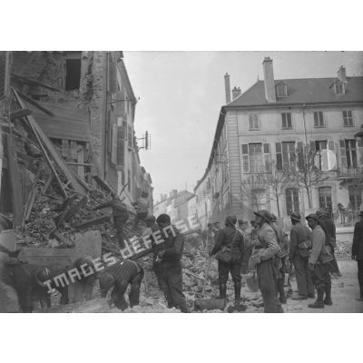 Des civils et des hommes de la défense passive évacuent les gravats d'une maison détruite par le bombardement allemand sur la ville de Nancy.