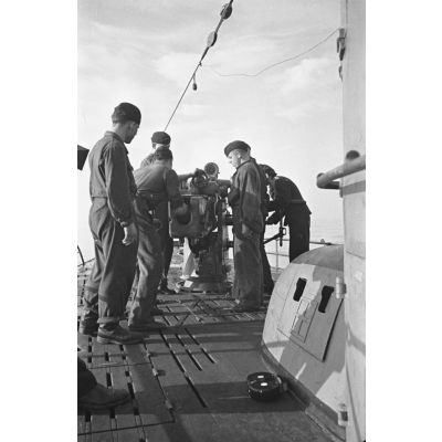 A bord d'un sous-marin allemand (U-boot), les sous-mariniers s'exercent au canon de 10,5 cm SK C/32 (Schnellladekanone - canon à chargement rapide).