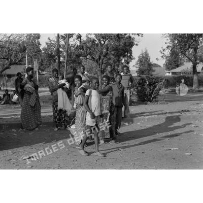Des jeunes femmes et des enfants attendent l’autobus sur le bord de la route à Lubumbashi. <br>[Description en cours]