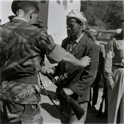 [Le général de brigade Jacques Massu remet un fusil à un Algérien, 1956-1958.]