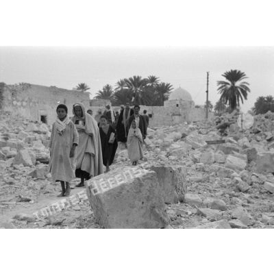 Dans Gafsa en ruines, la population, hommes et enfants, parcourt les ruines.