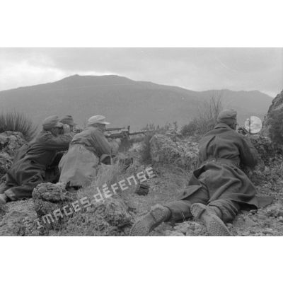 Un groupe de soldats est allongé au sommet d'une colline, tir d'une mitrailleuse MG-34.