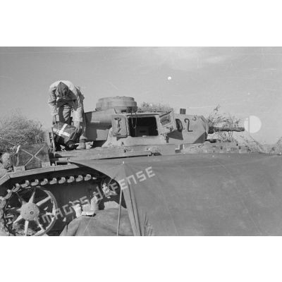Un caporal (Gefreiter) du Panzer Regiment 5 (Pz.Rgt-5) sur un char Panzer III (Pz-III Ausf H) camouflé et auquel est fixée la tente de l'équipage.
