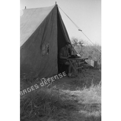  Un soldat tape à la machine à écrire au seuil d'une tente.