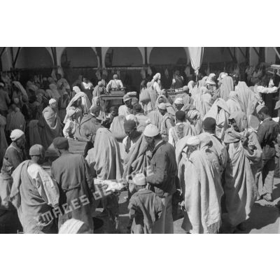 A Tripoli, un caporal allemand circule dans les allées d'un marché, rentre en contact avec les marchands.