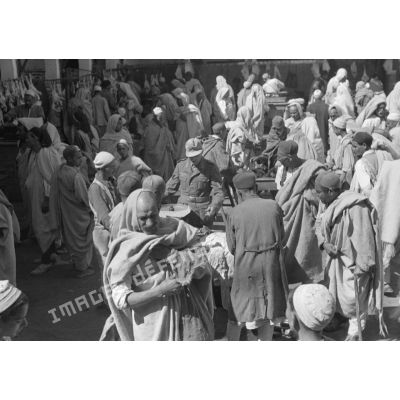 A Tripoli, un caporal allemand circule dans les allées d'un marché, rentre en contact avec les marchands.