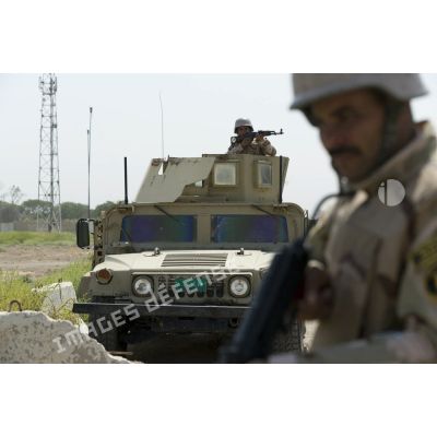 Un soldat irakien mène un contrôle de zone autour d'un véhicule blindé Humvee à Bagdad, en Irak.