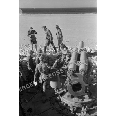 Le général Erwin Rommel inspecte une batterie d'artillerie abandonnée par ses servants, on remarque l'absence de culasse au canon.