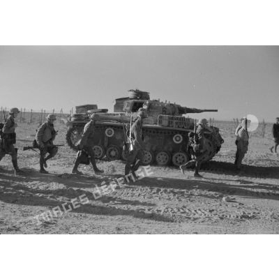 Des soldats du Panzer-Pionier-Bataillon (Pz.Pion.Btl-33) se dirigent vers des Panzer III (Pz-III Ausf-F) du 6-Panzer.Regiment-8 de la 15-Panzer.Division.