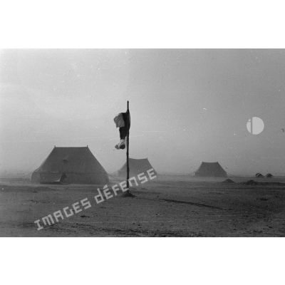 Un hôpital de campagne formé de tentes sous une tempête de sable. Le drapeau à croix rouge.