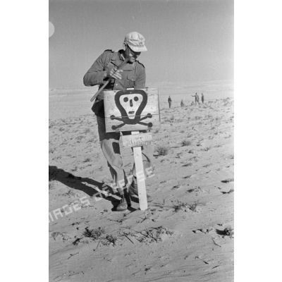 Un soldat installe le panneau prévenant de la présence d'un champ de mines.