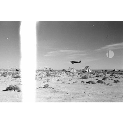 Des avions de transport Junkers Ju-52 passent au-dessus de tentes dans le désert.