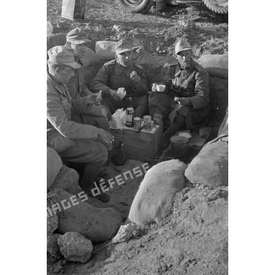 Un groupe de soldats mange dans un trou.