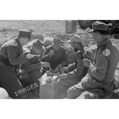 Un groupe de soldats mange confortablement installé dans un trou.