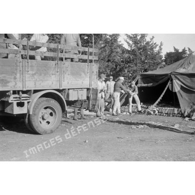 Des soldats déchargent du pain d'un camion et l'entreposent sous une tente.