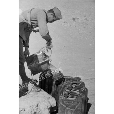 Des soldats italiens tirent de l'eau d'un puits et remplissent des contenants dont des jerricans.