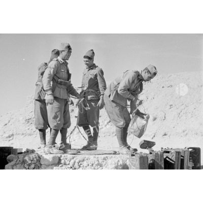 Des soldats italiens tirent de l'eau d'un puits et remplissent des contenants dont des jerricans.