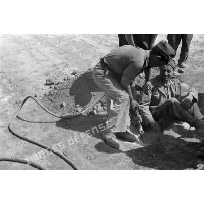 Les soldats italiens creusent un trou à l'aide d'un marteau-piqueur.