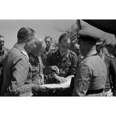 Conférence autour de documents tenus par un capitaine de la Panzerwaffe.