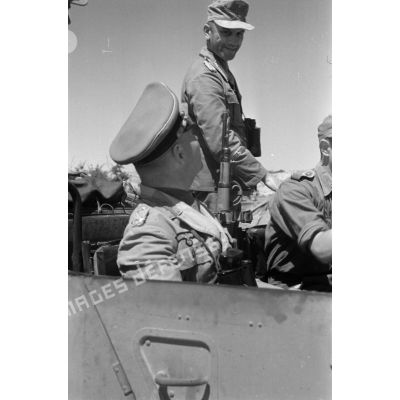 Erwin Rommel, assis à la droite du chauffeur d'une voiture Kfz-15, parle au général Alfred Gause, debout dans la même voiture.