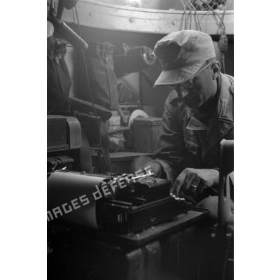A l'intérieur d'un véhicule blindé, un soldat tape sur une machine à écrire.