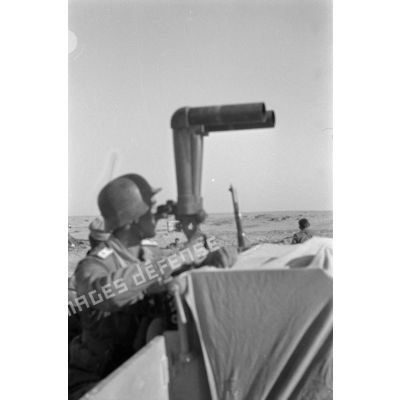 Un officier observe le terrain avec un binoculaire.