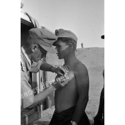 Un médecin militaire vaccine des soldats près d'un camion ambulance Kfz-15.