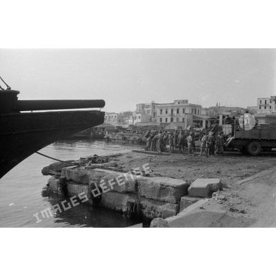 Dockers et soldats travaillant sur les quais du port de Tobrouk.