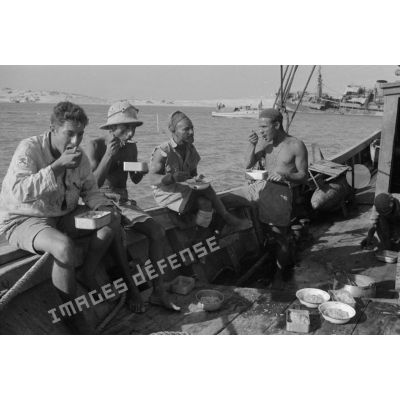 Des soldats italiens mangent sur le pont d'un bateau.