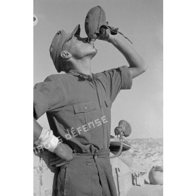 Un soldat boit le contenu d'une gourde.