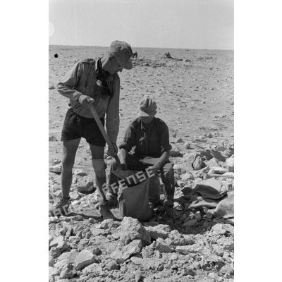 Deux soldats remplissent un sac de sable.