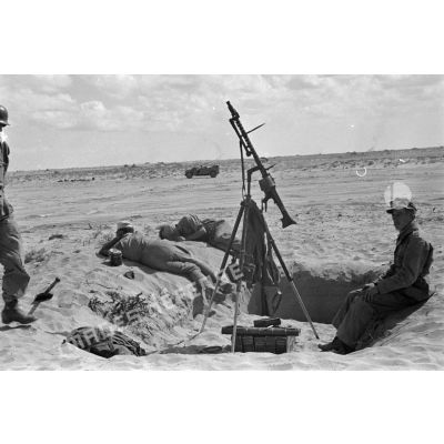 Les servants d'une mitrailleuse MG-34, installée sur un affût tripode pour le tir anti-aérien, se reposent.