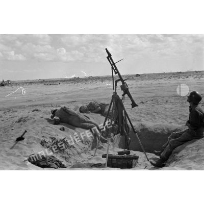 Les servants d'une mitrailleuse MG-34, installée sur un affût tripode pour le tir anti-aérien, se reposent.