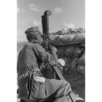 Un officier italien observe le terrain à l'aide d'un binoculaire (jumelles).