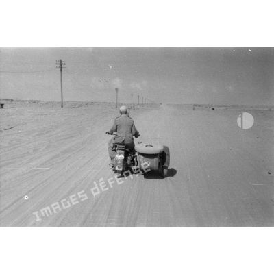 Un side-car BMW R75 roule dans le désert, le long de la piste baptisée du télégraphe.