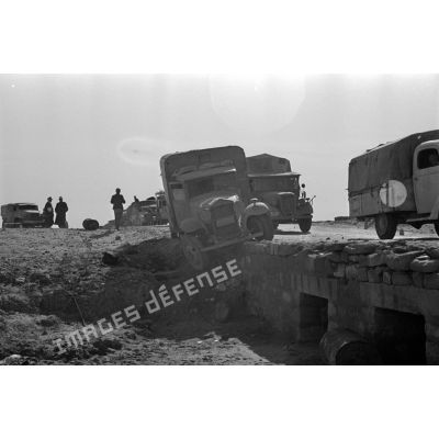 Passage d'un pont par une colonne de véhicules allemands et italiens, un camion accidenté a glissé hors du pont.