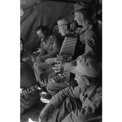Moment de détente dans un abri pour des soldats allemands. Jeu d'échec et accordéon. Repas.