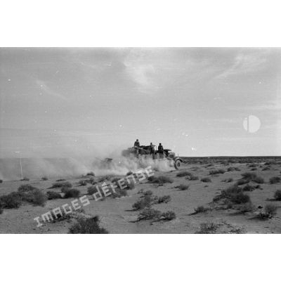 Un semi-chenillé SdKfz-7 qui tracte un canon de FlaK de 2 cm passe dans le désert.