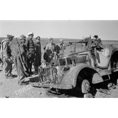 Des officiers et soldats allemands, dont l'équipage du Fw-58 entourent la carcasse d'une Steyer 1500 A.