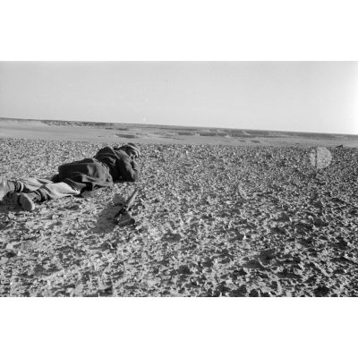 Un soldats allongé sur le sol observe le terrain.