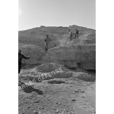Un  caméraman, un capitaine médecin de la Luftwaffe suivis de deux soldats descendent une colline.